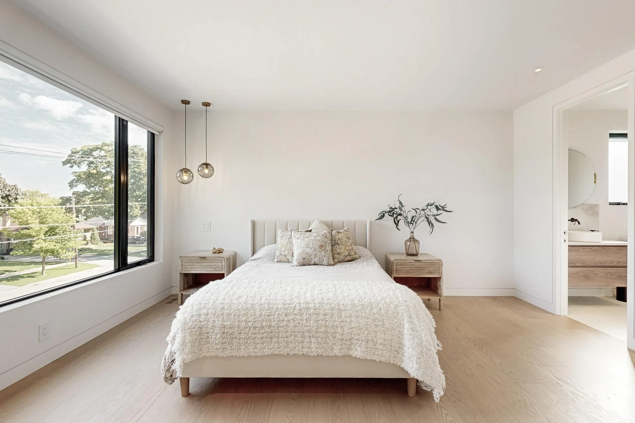 Calm bedroom with a light wood bed, glass pendant lights, and a black-framed window.