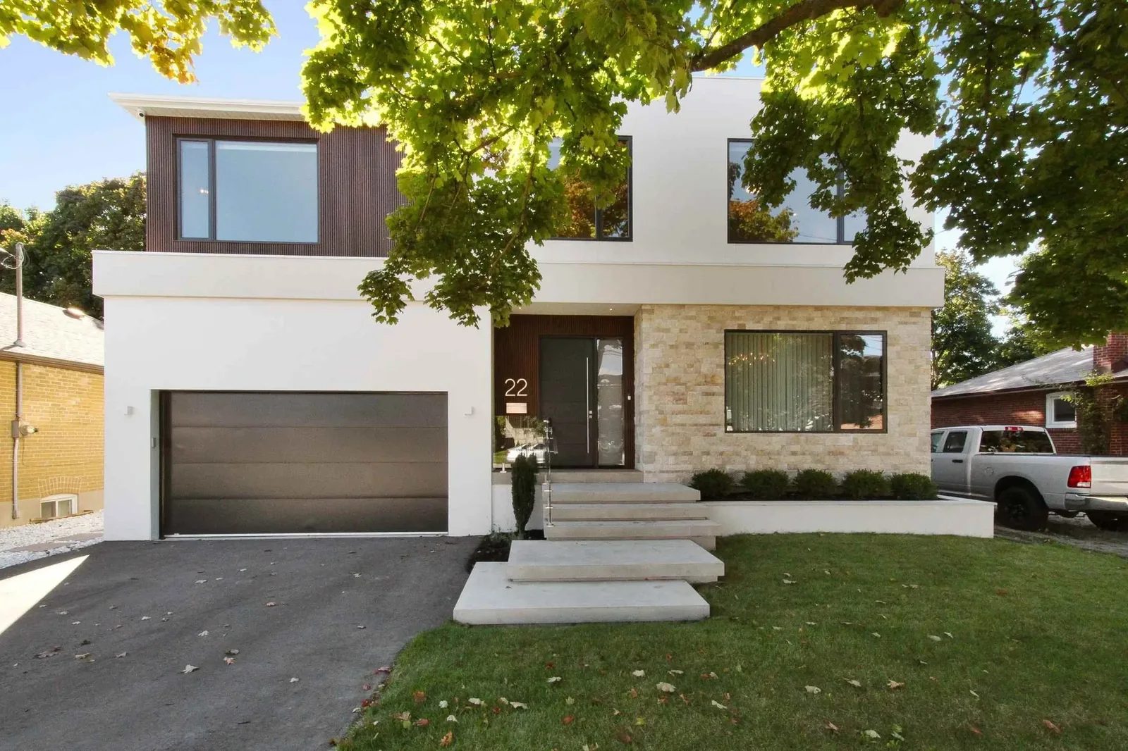 Street view of a modern two-storey custom home with a stone, stucco, and dark wood facade.
